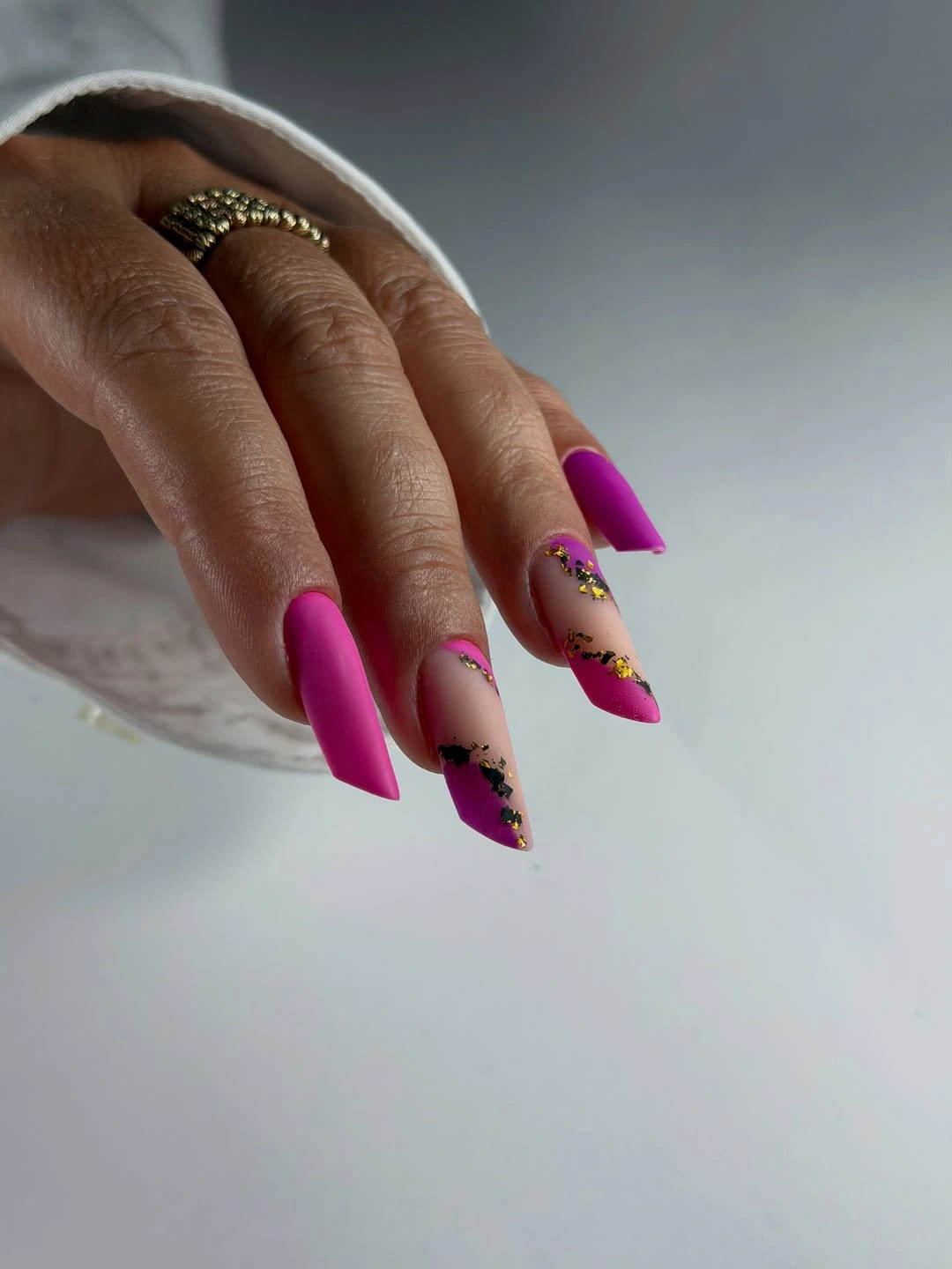 Long magenta nails with nude accents and dark floral-like details
