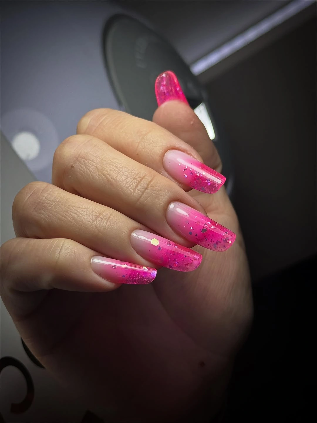 Long square pink nails with transparent-looking tips and dark specks