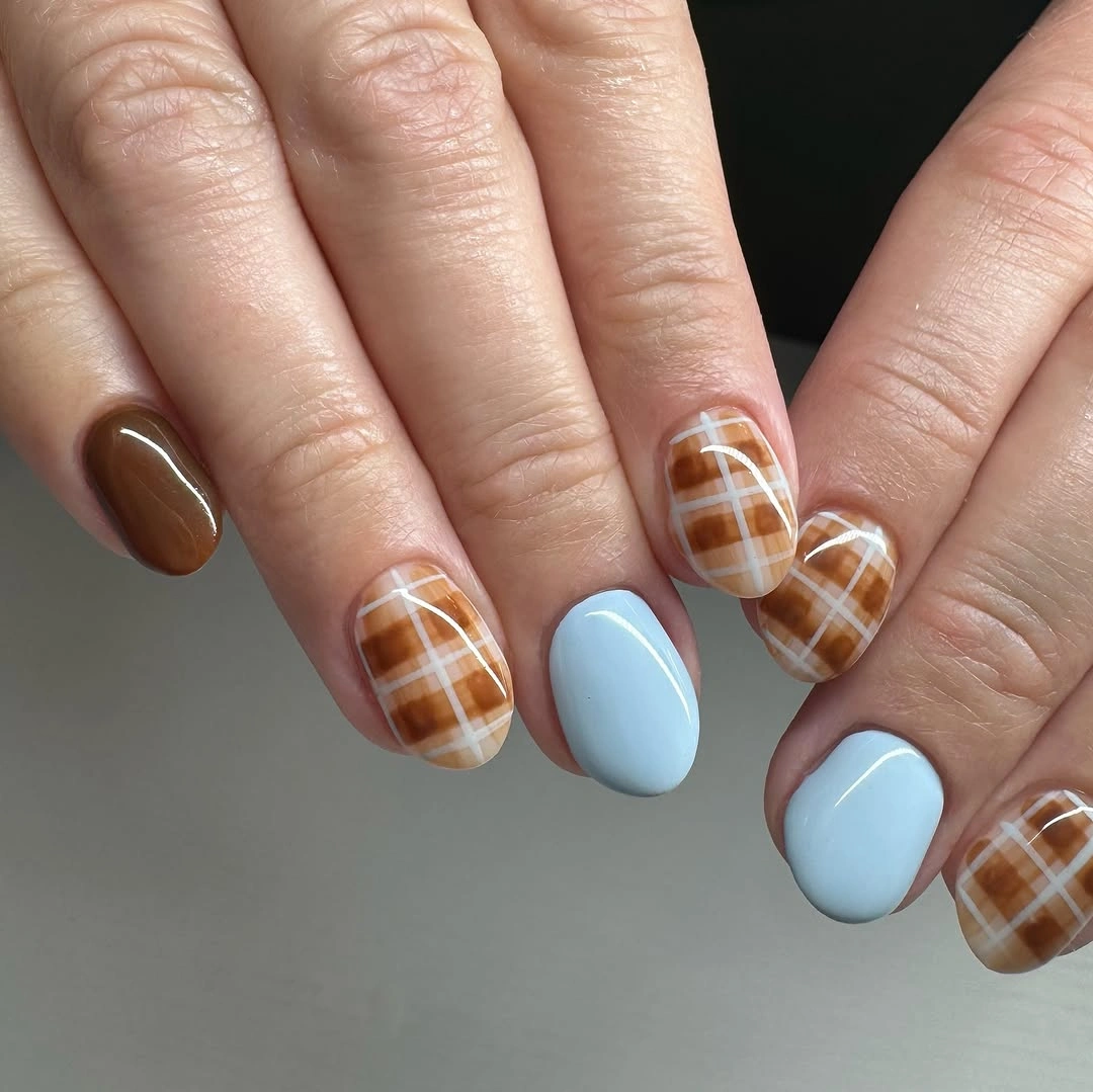 Short rounded nails with pale blue and brown plaid accents