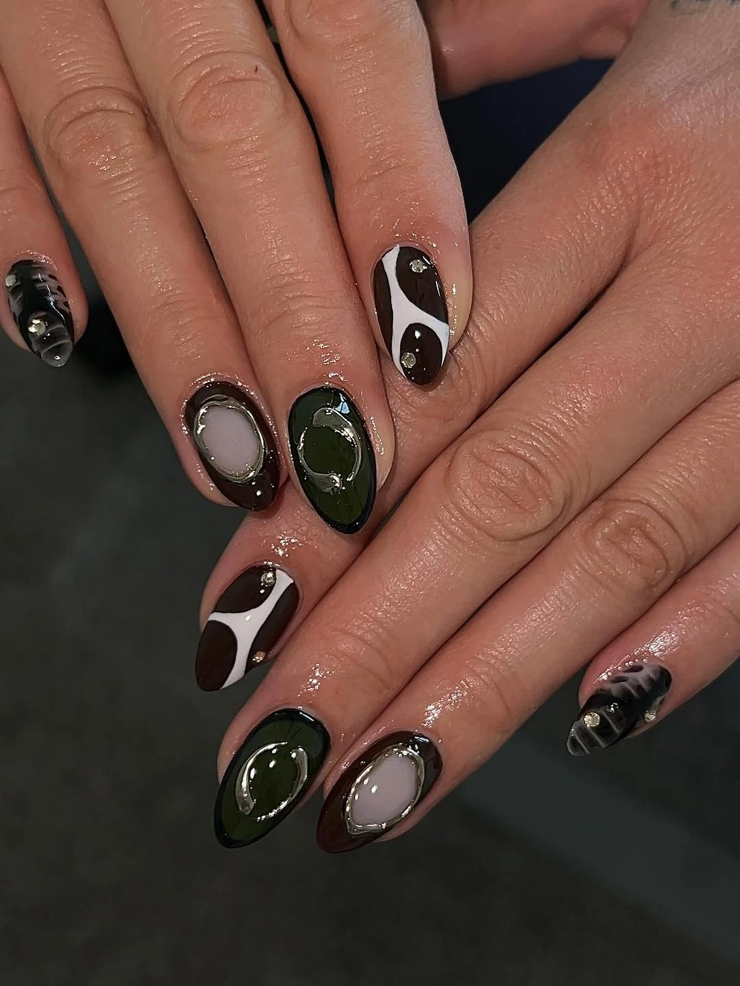Almond nails with dark swirls oval frames and metallic-looking outlines