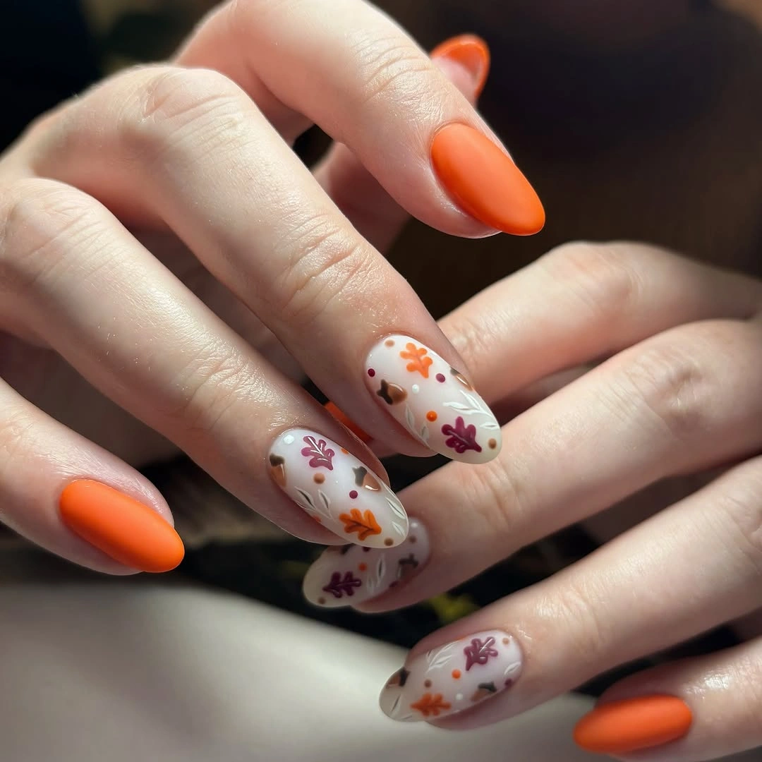 Orange almond nails with neutral scattered leaf-like motifs