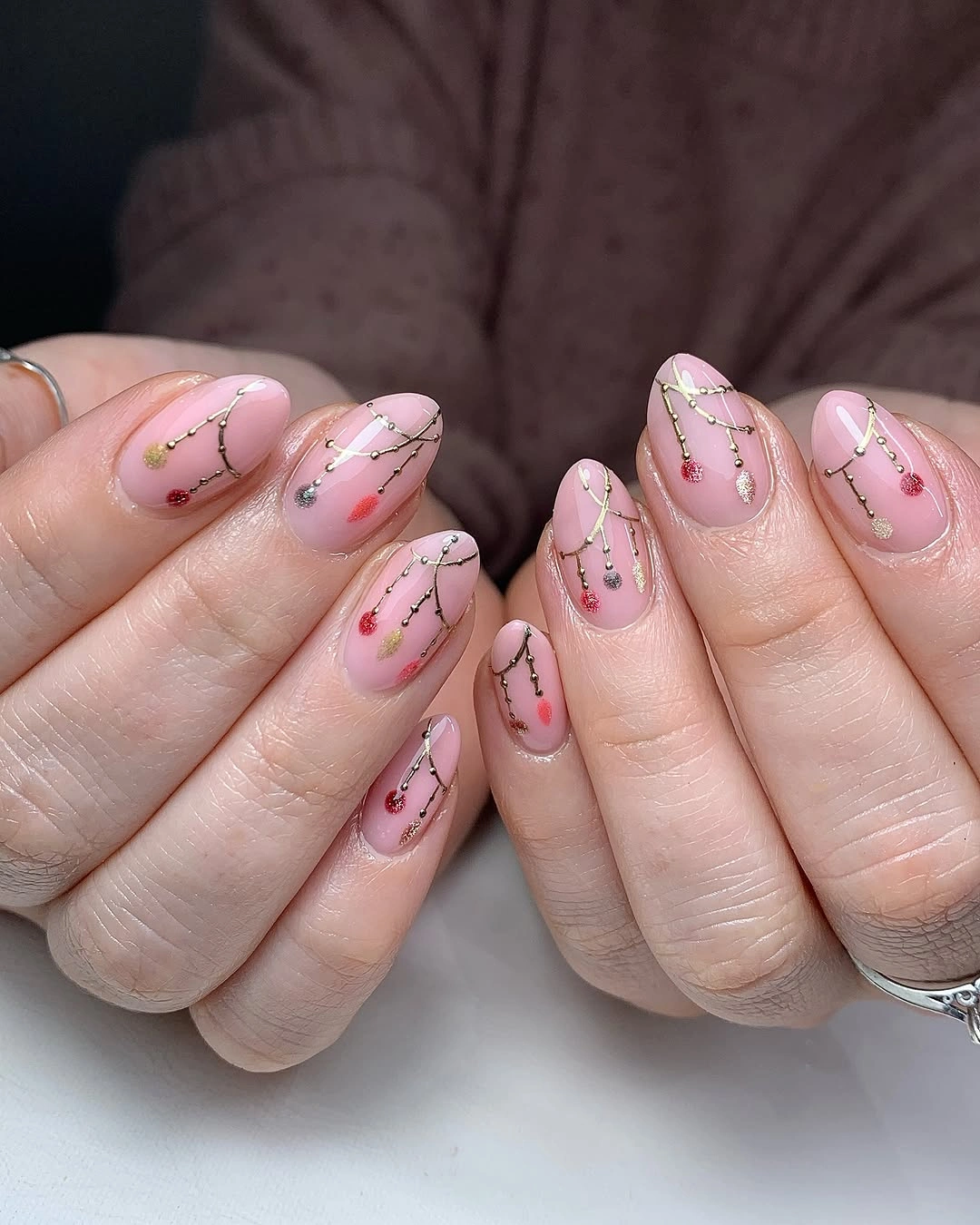 Soft pink almond nails with branching lines and colored dots
