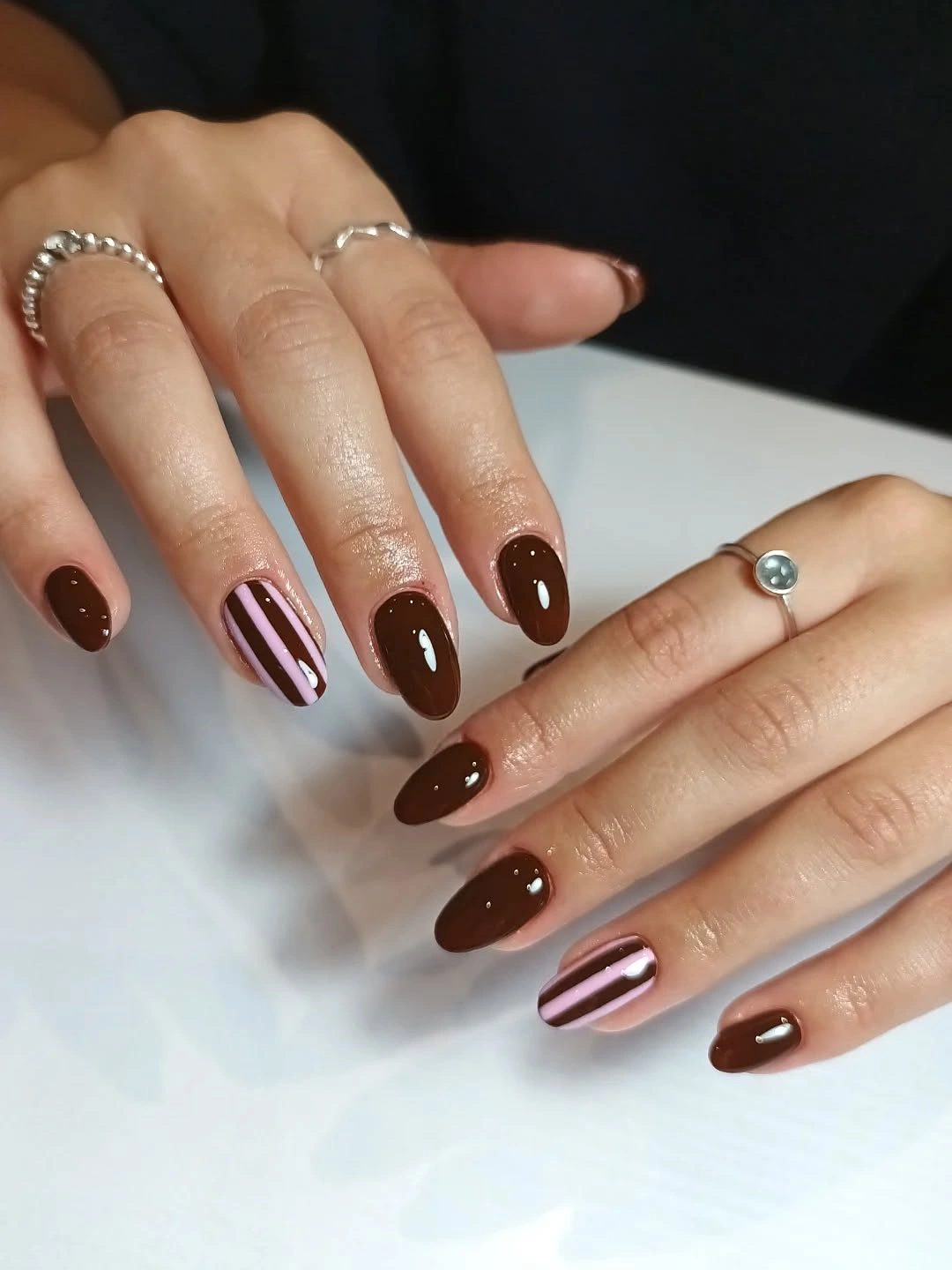 Glossy chocolate-brown almond nails with slim pink striped accents