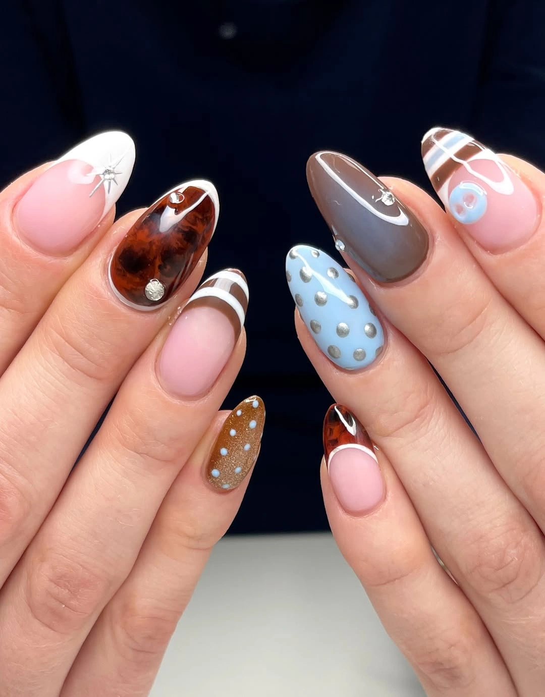 Almond nails with brown, blue, dotted, plaid, and curved designs