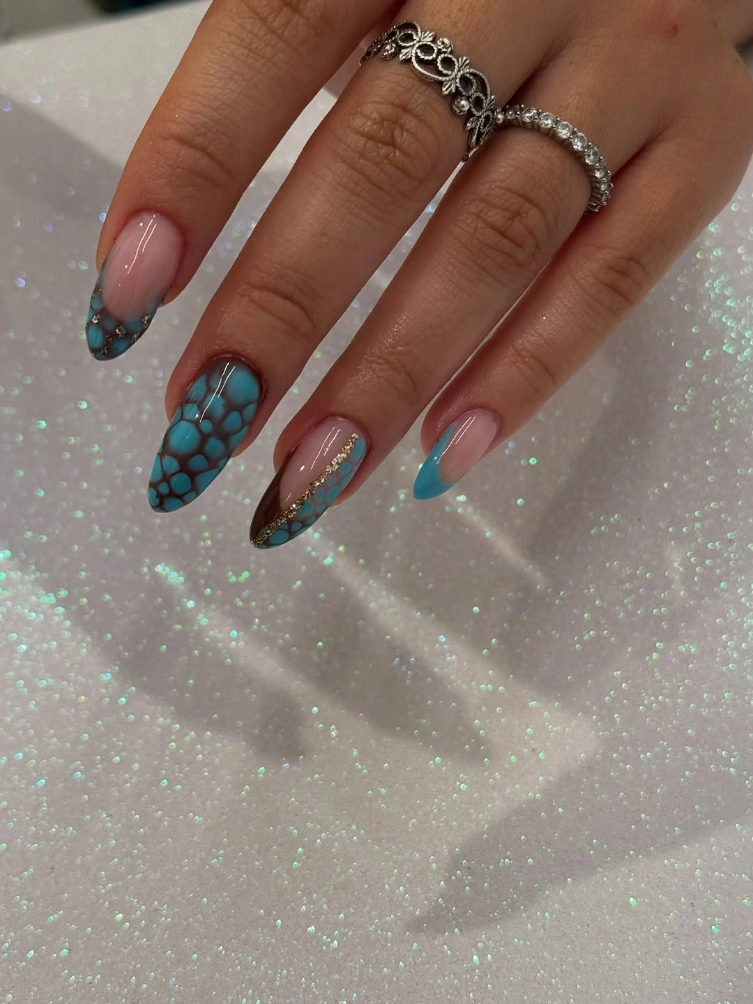 Long almond nails with turquoise scale-like pattern and brown accents