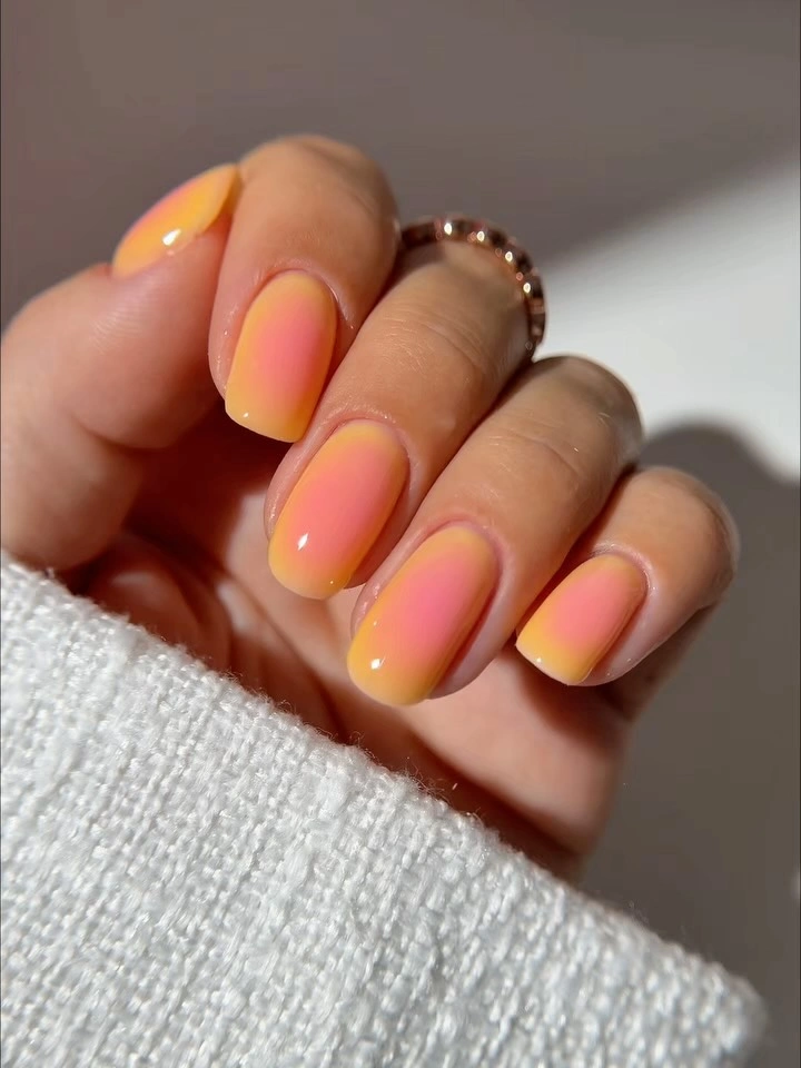 Rounded-square nails fading from coral pink to orange-yellow edges