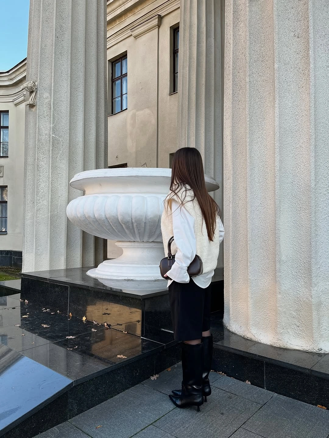 Light upper layer, dark skirt, tall black boots, small bag