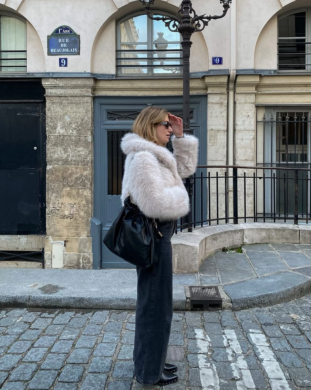Cream shaggy jacket, dark wide pants, black boots, large bag
