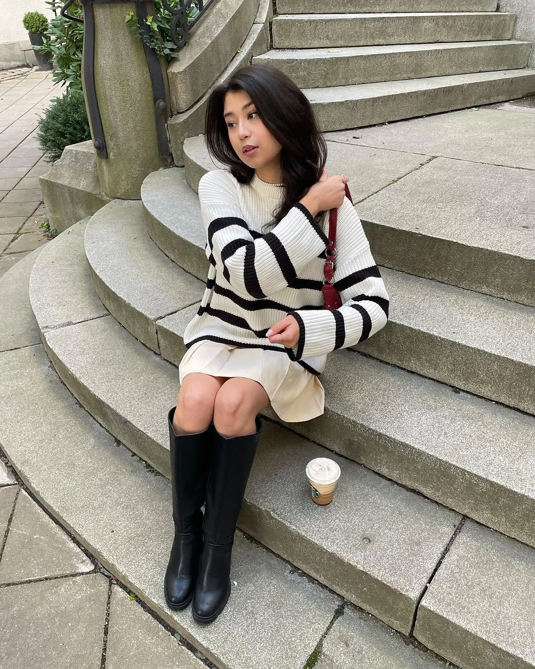 Striped sweater, cream short skirt, black boots, red shoulder bag
