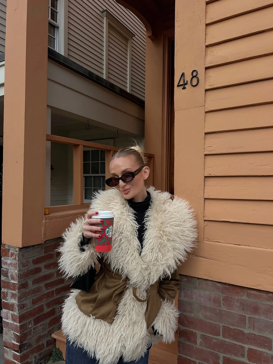 Tan jacket with cream panels, black top, dark jeans