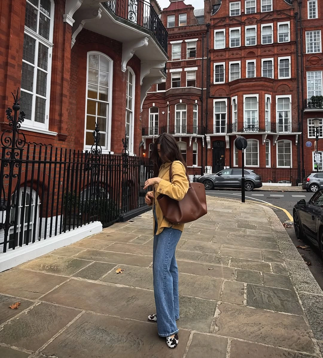 Yellow jacket, blue jeans, black sneakers, brown shoulder tote