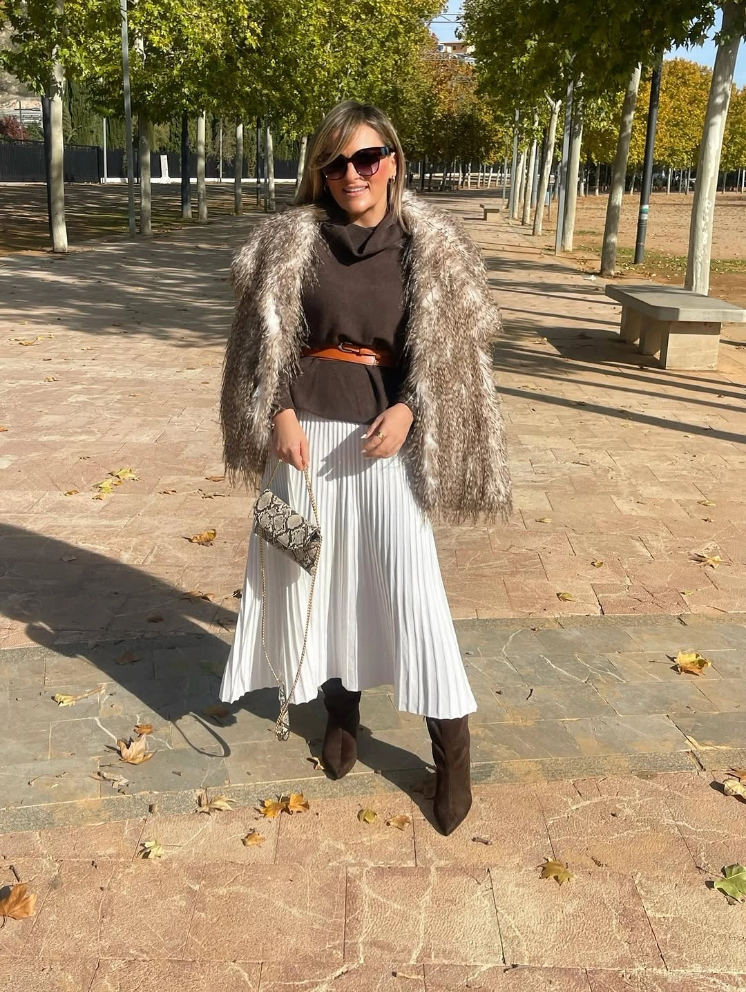 Shaggy taupe jacket, dark top, white pleated skirt, tall boots