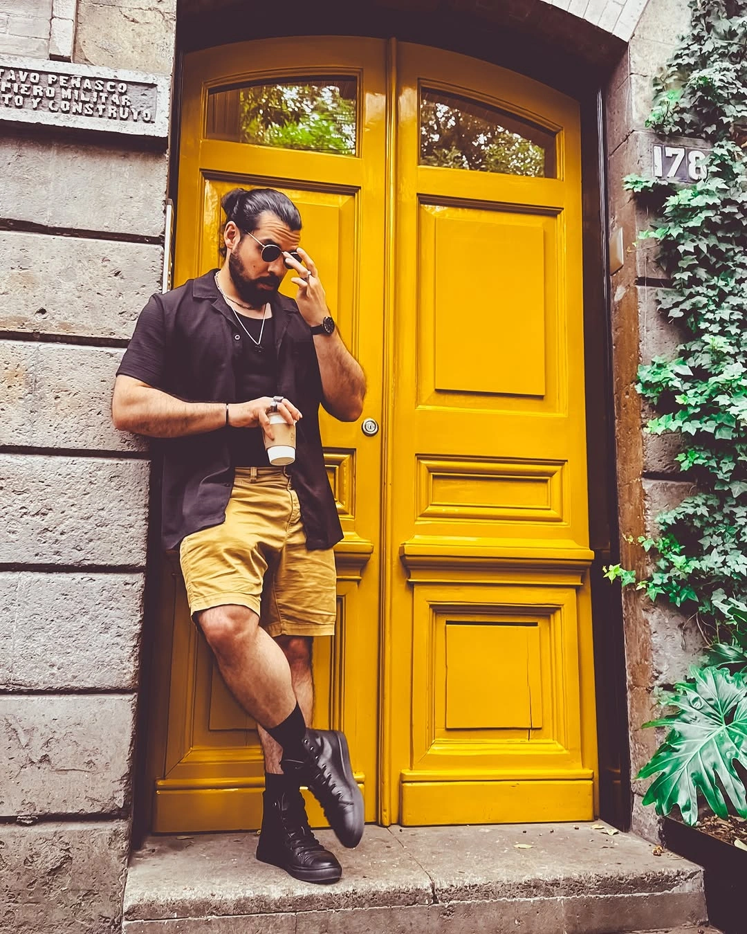 Black polo with mustard shorts and black boots