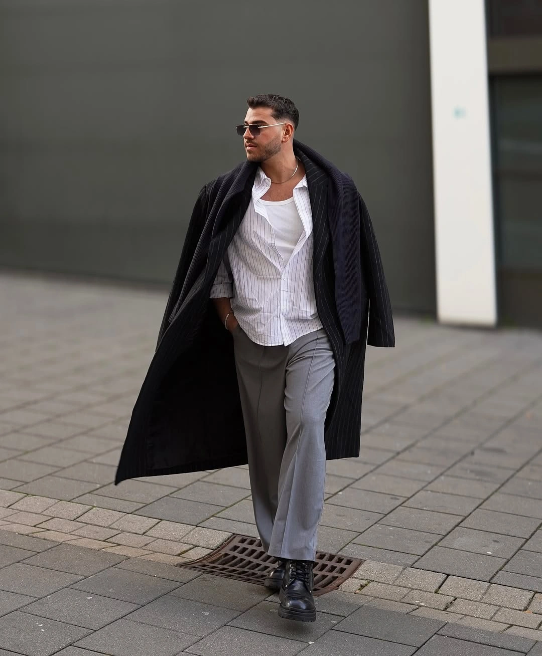 Long black coat over white shirt and gray trousers