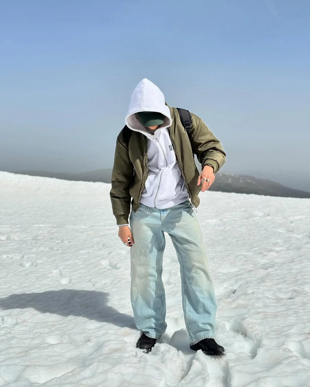Olive bomber over white hoodie with pale blue jeans