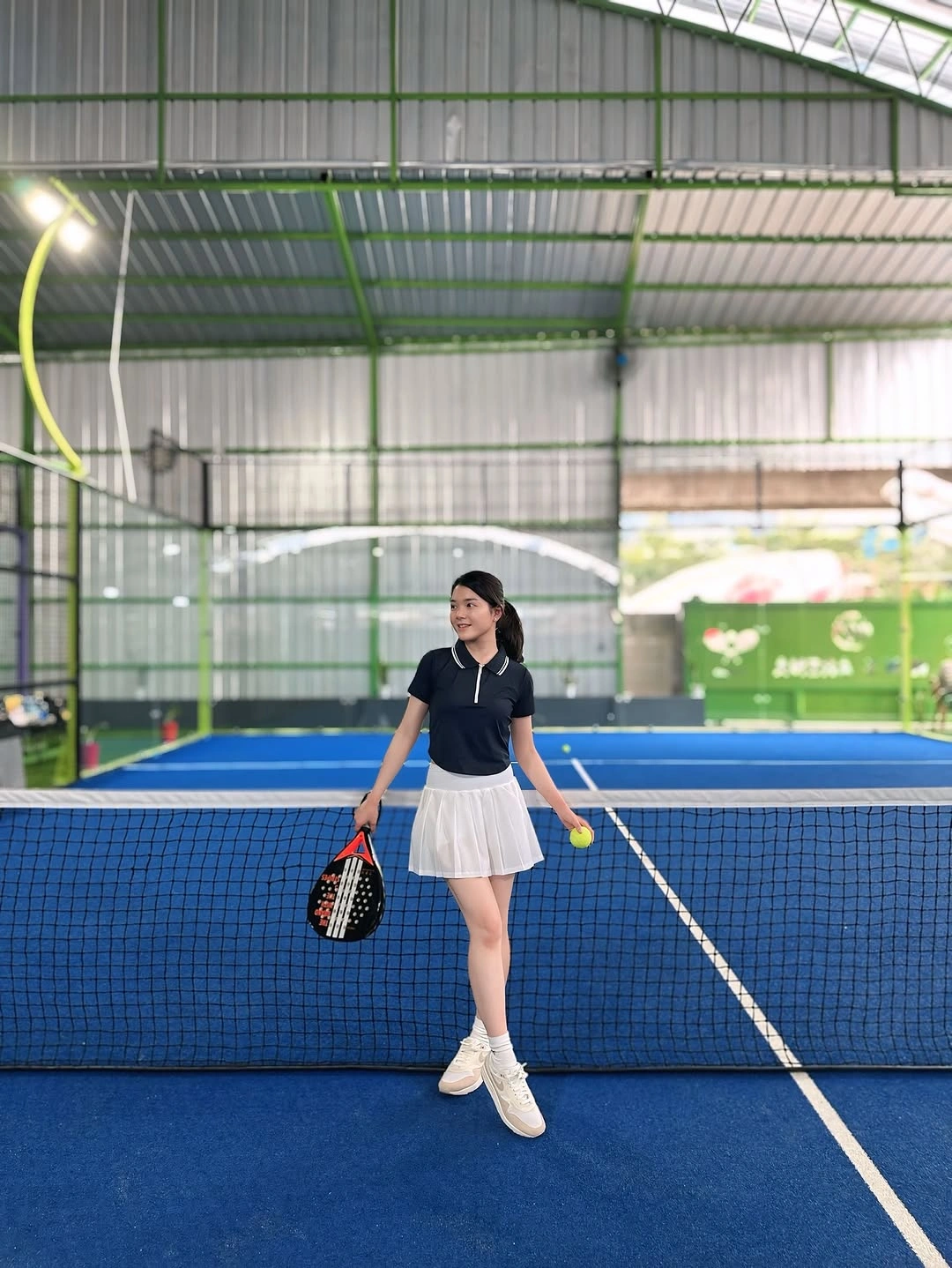 Navy polo with white pleated skirt and white trainers