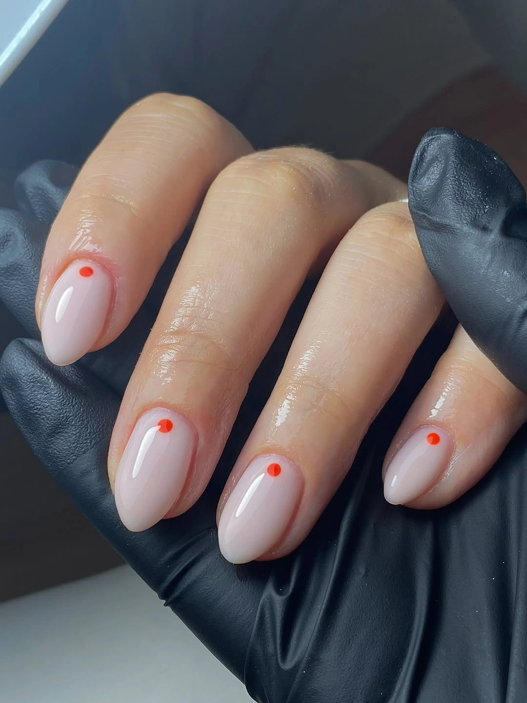 Short milky nude almond nails with one tiny orange dot on each nail