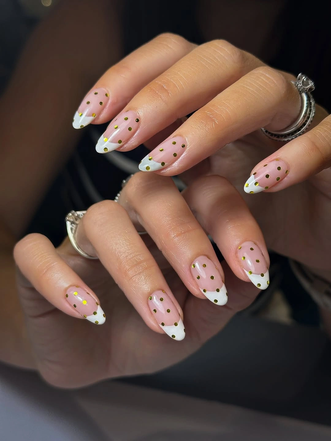 Nude almond nails with white French tips, yellow touches, and black dots