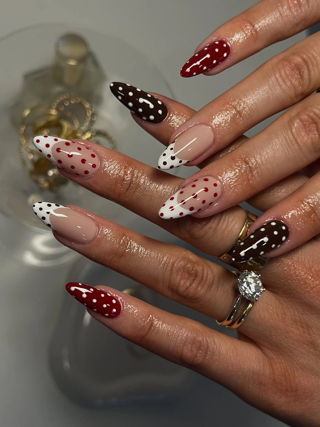 Long pointed nude nails with burgundy brown white and red dotted sections