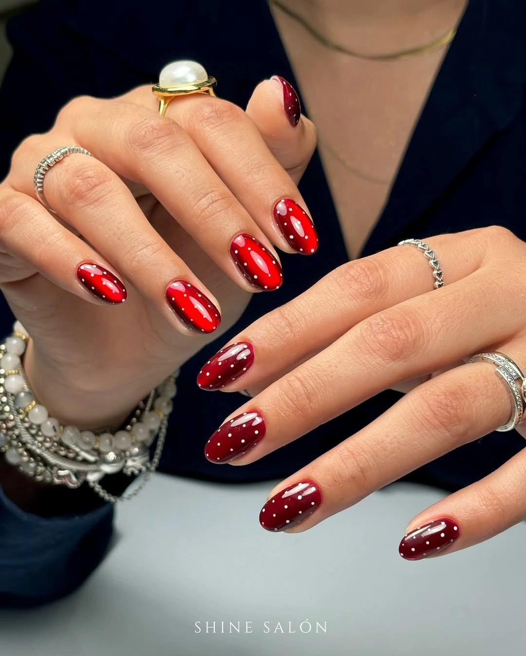 Long glossy red and burgundy almond nails with small white dot highlights