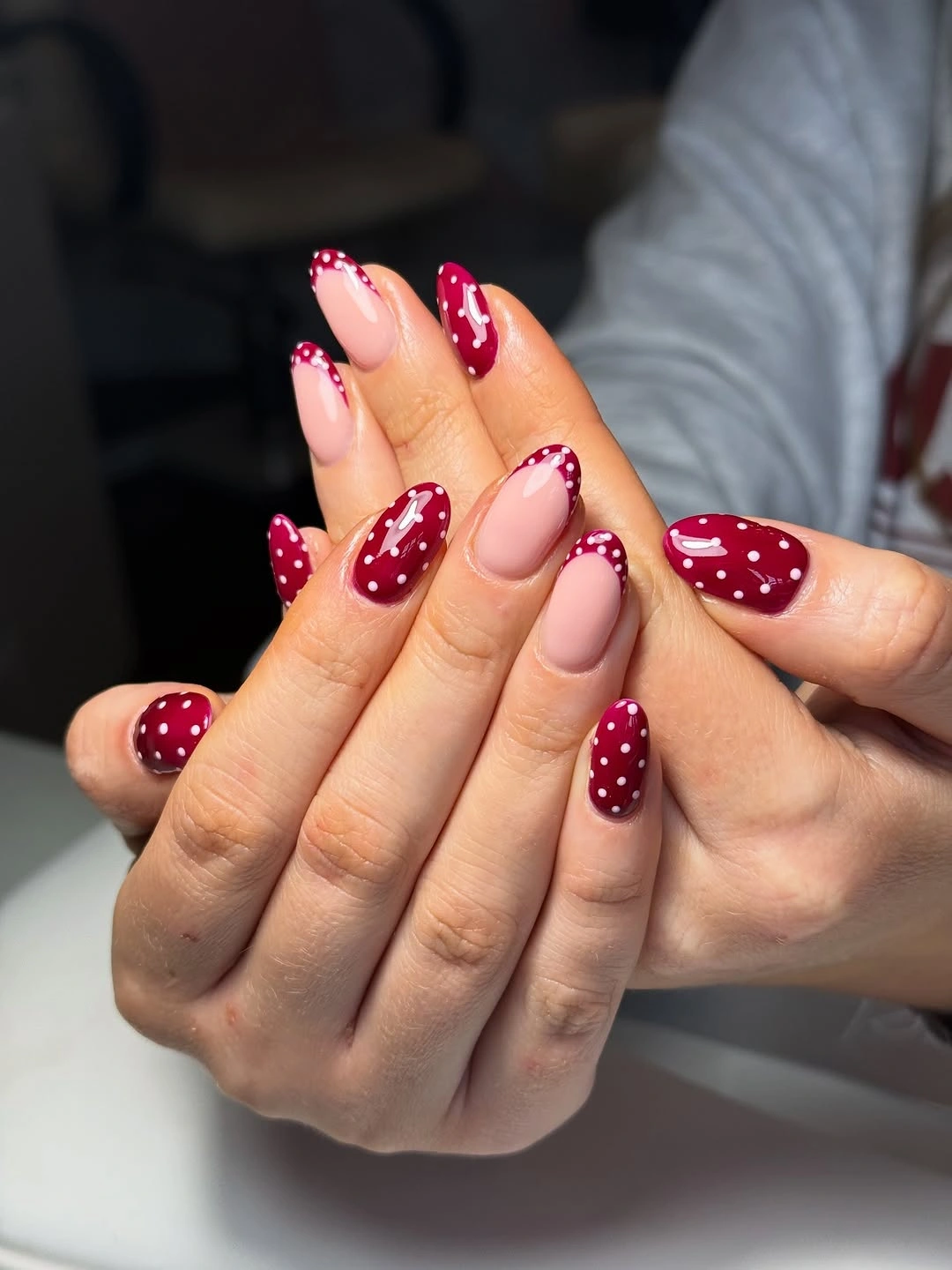Long burgundy almond nails with white dots and pale pink negative-space accents