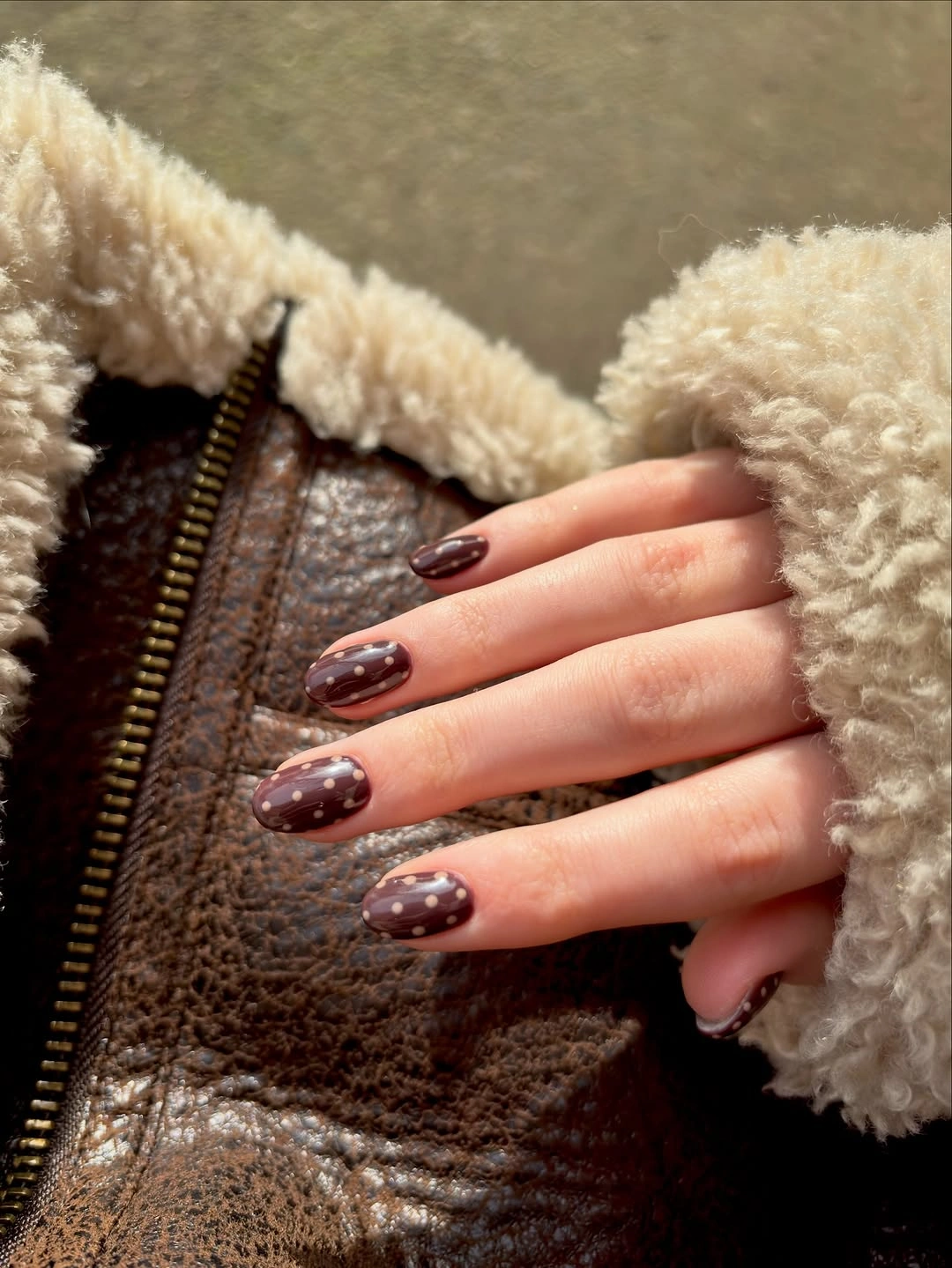 Deep glossy brown medium-short nails with subtle pale pink and brown dots