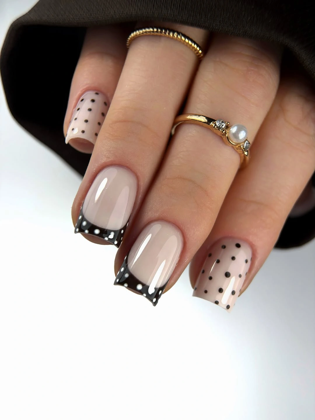 Medium nude almond nails with black-edged white dotted angular tips