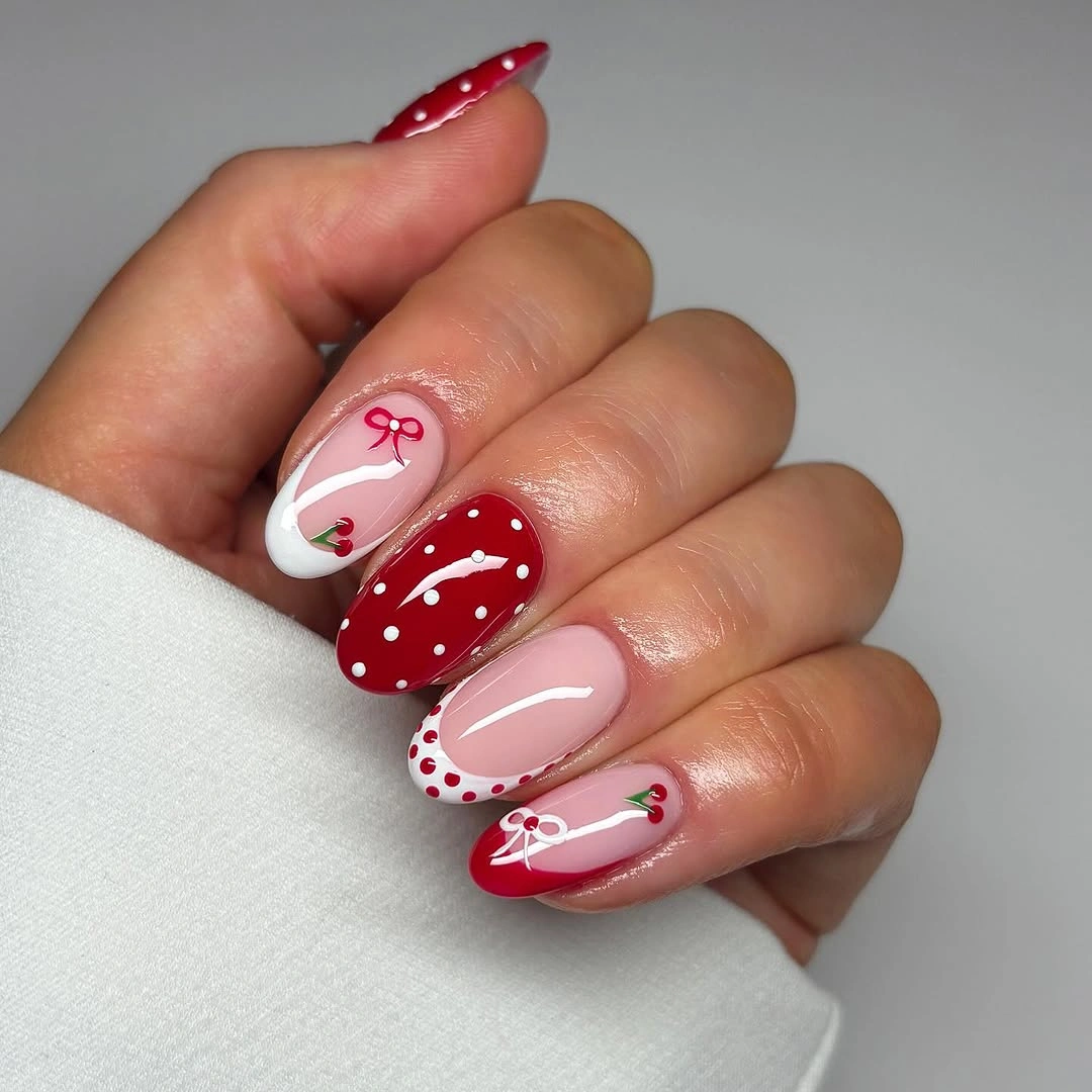 Almond red pink and white nails with dots bows and fruit-inspired details