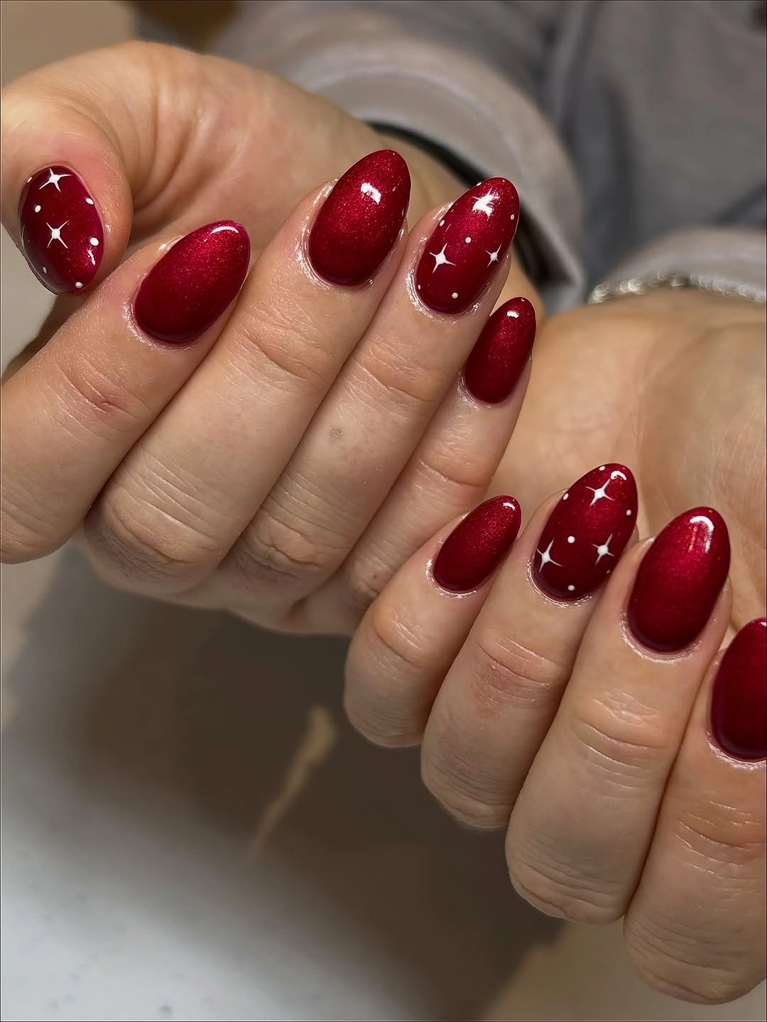 Short oval ruby red nails with small white starbursts