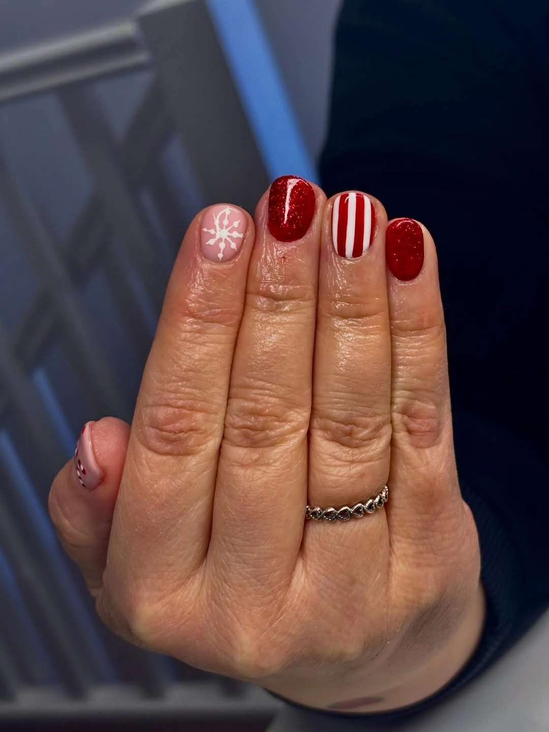 Short rounded red nails with snowflake and striped accents