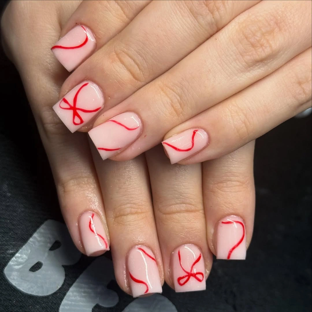 Short square pale pink nails with thin red ribbon linework