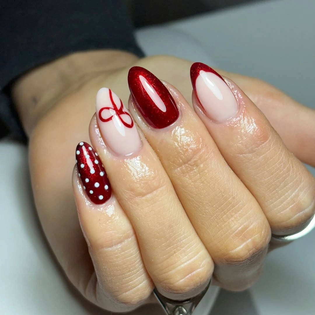 Medium almond red and pale nails with dots and bow linework