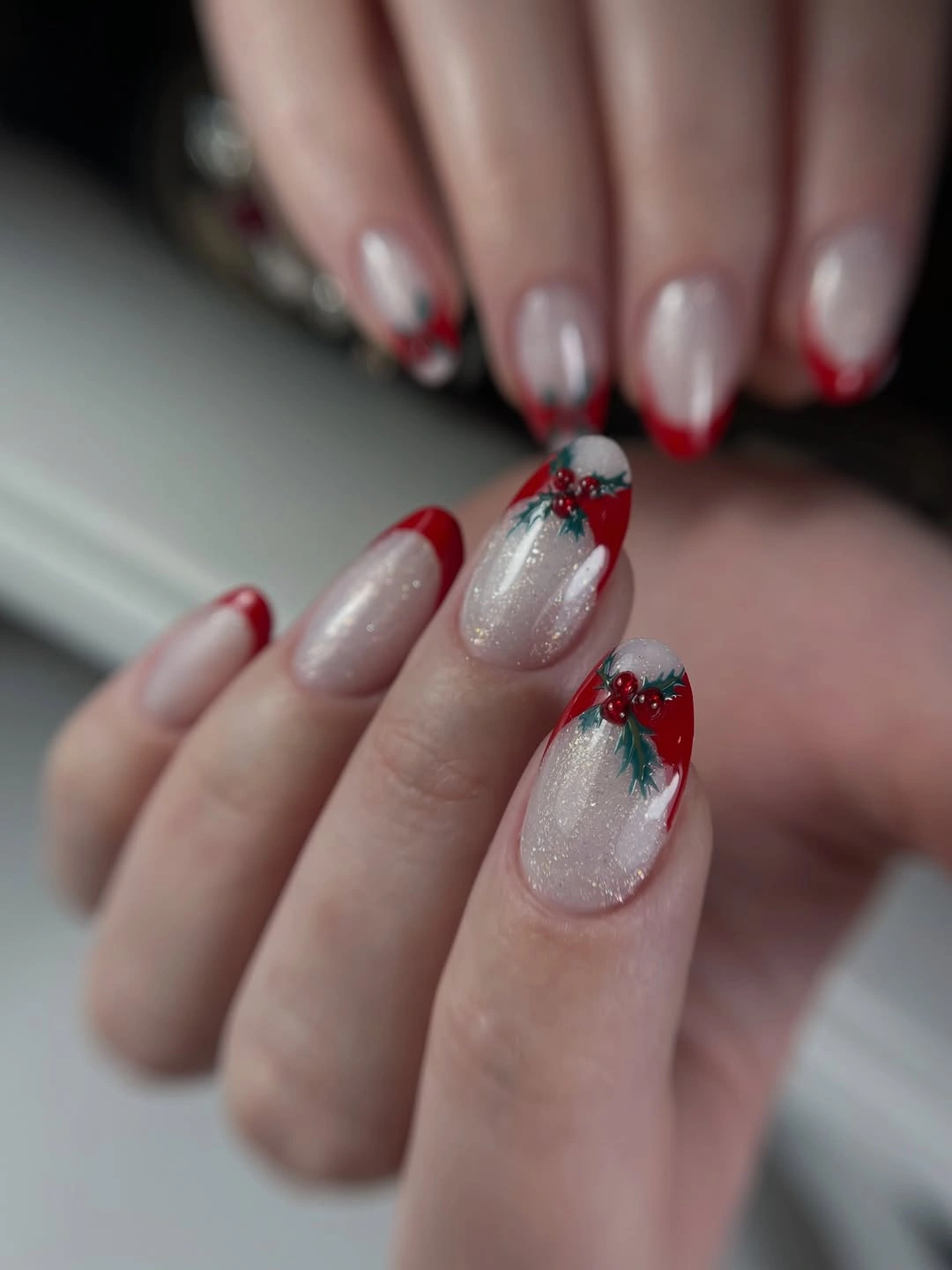 Almond nails with red tips and small berry-like green accents