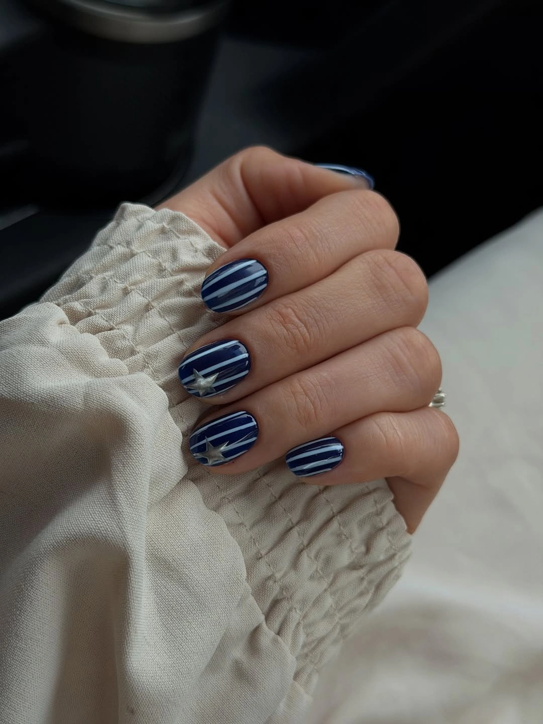 Dark navy short nails with pale stripes and star accents