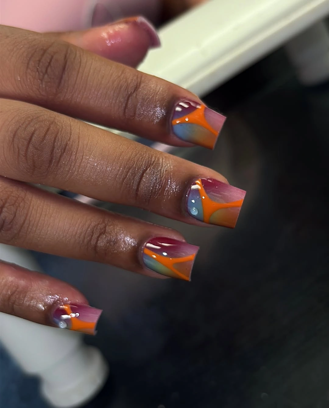 Square nails with orange magenta blue and purple curves