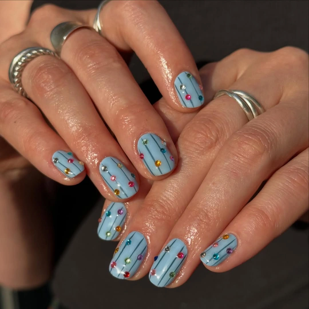 Light blue short nails with crisscross lines and colored dots
