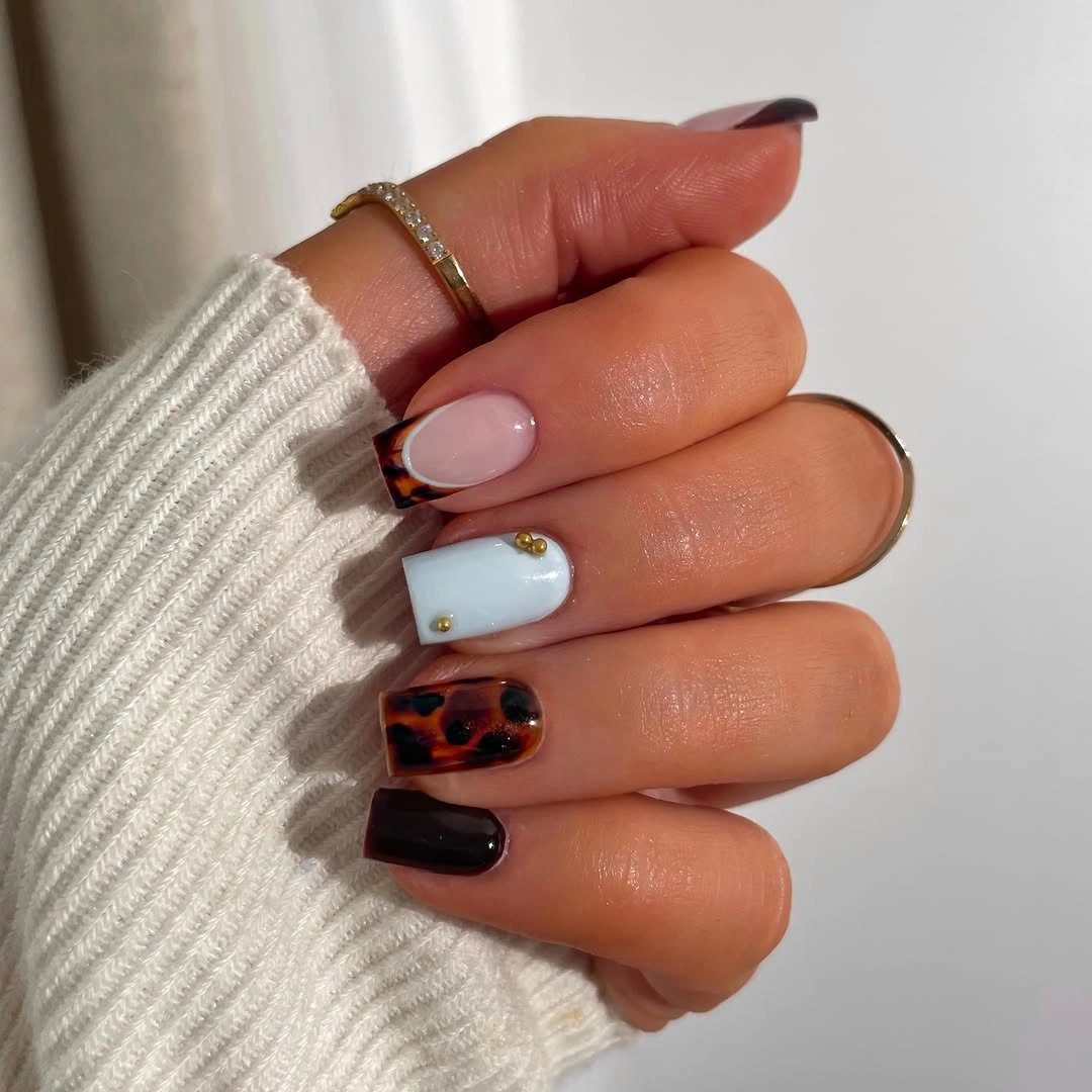 Mixed black pale blue and tortoise-like short nails with studs