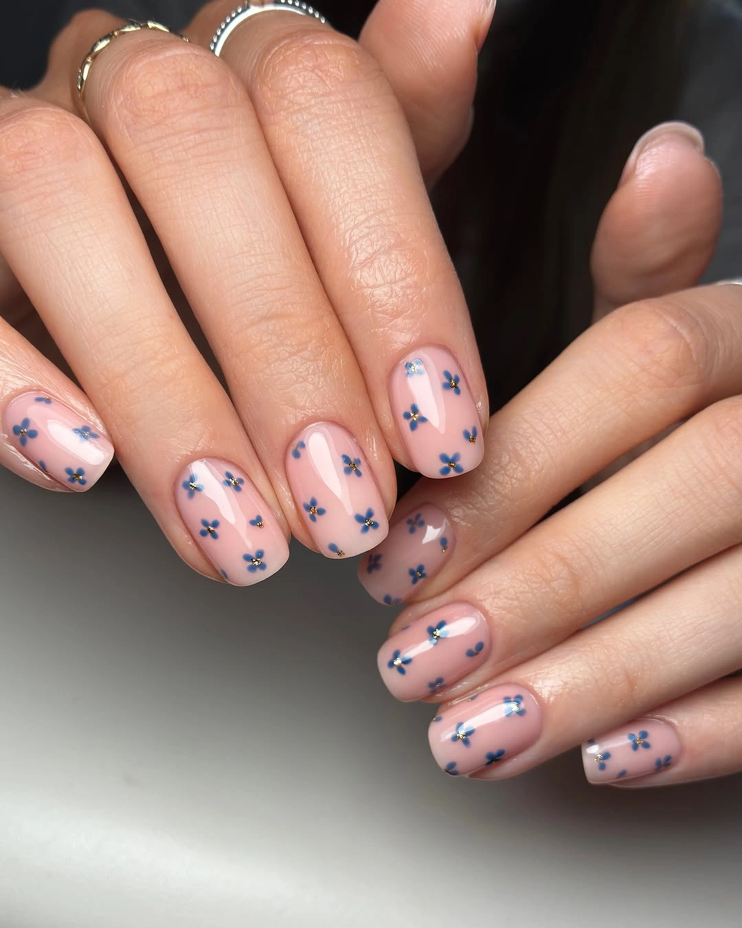 Nude pink short nails with small blue flower designs