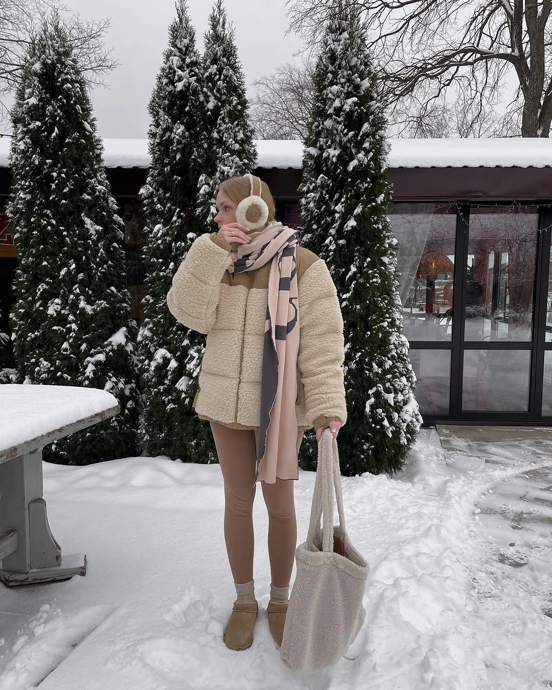 Cream puffer with beige scarf, pale pants, earmuffs, and white tote