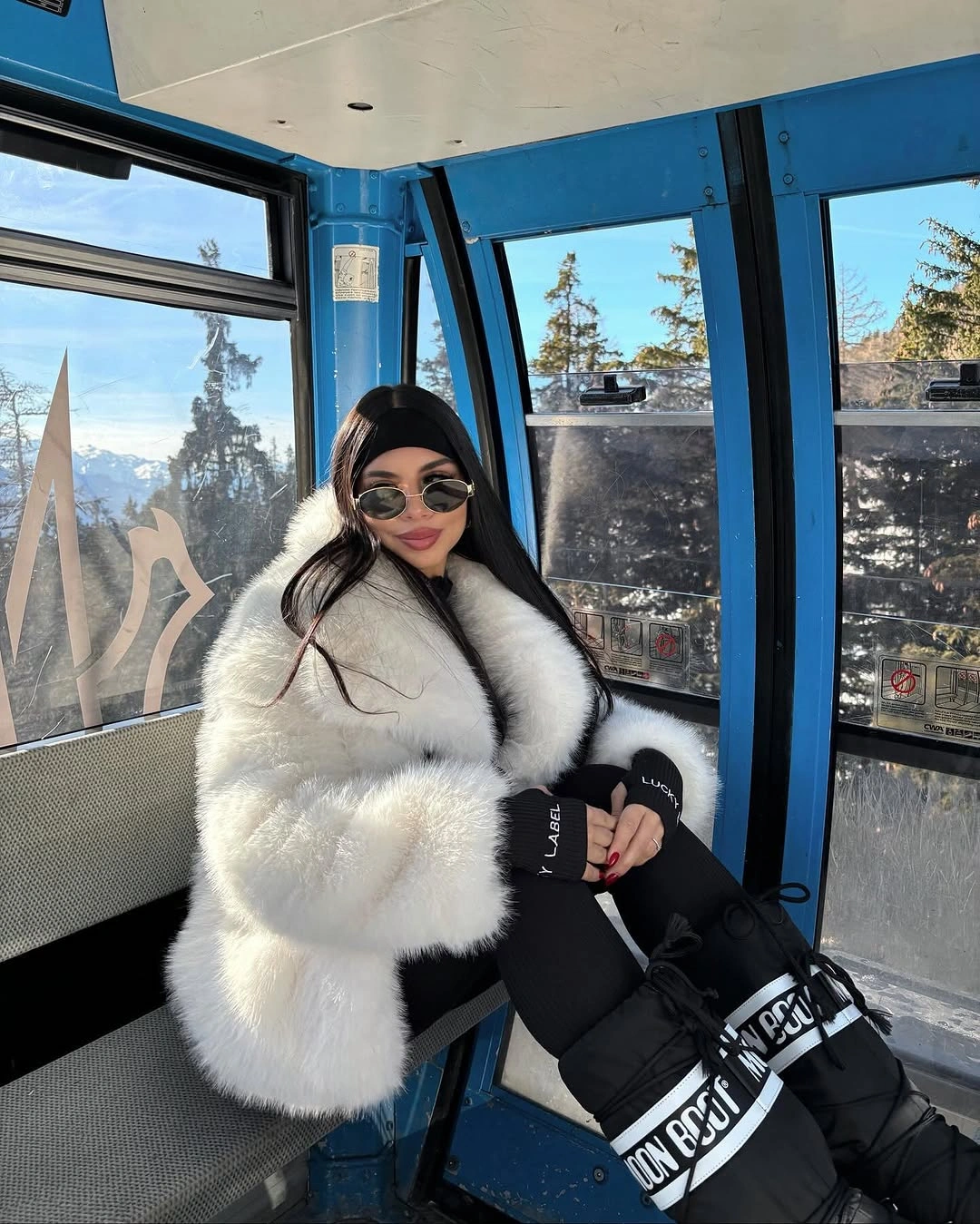 White fluffy jacket with black pants, black cap, and dark winter boots