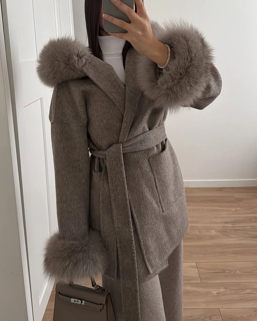 Taupe belted coat with plush-looking collar, cuffs, and matching handbag
