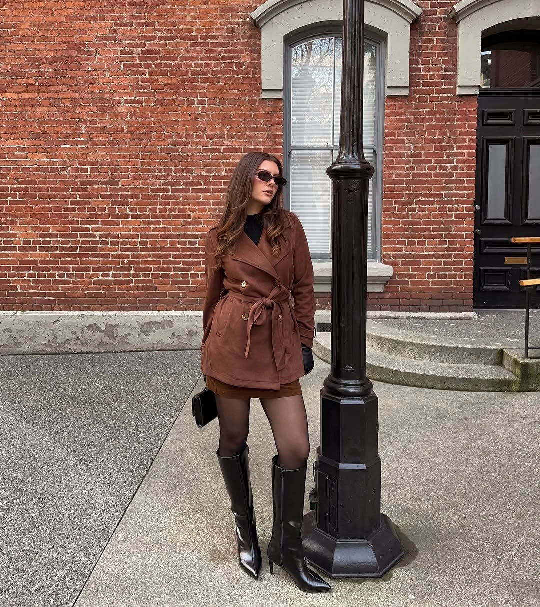 Brown belted short coat with black tights and knee-high boots