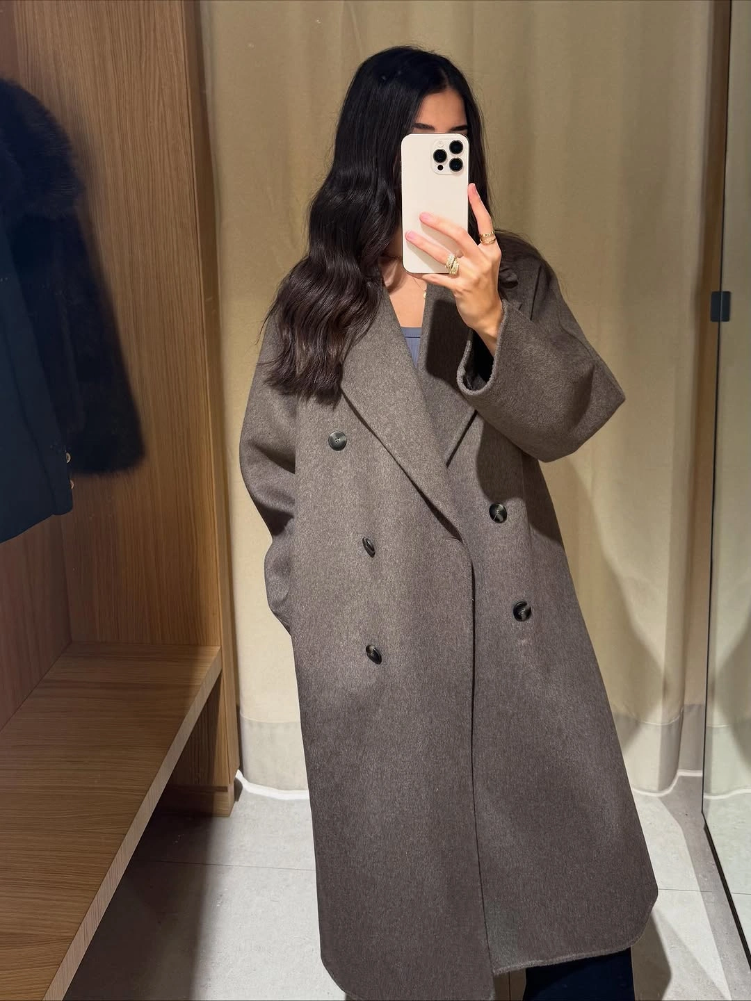 Brown-gray double-breasted long coat over dark clothing indoors