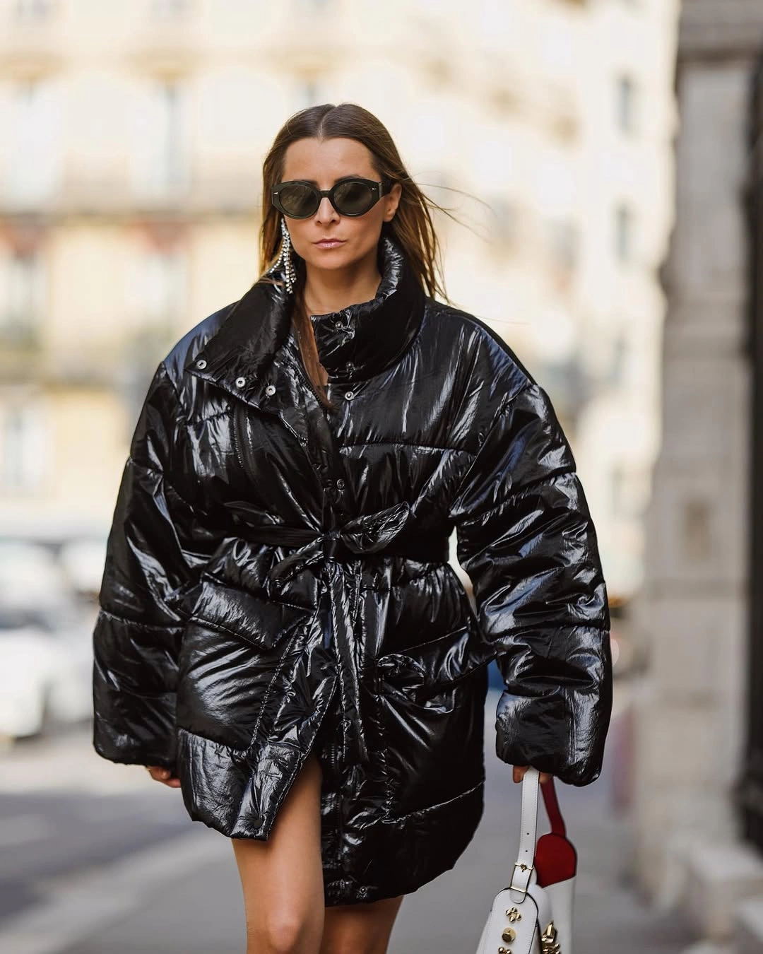 Shiny black belted puffer with sunglasses and small handbag