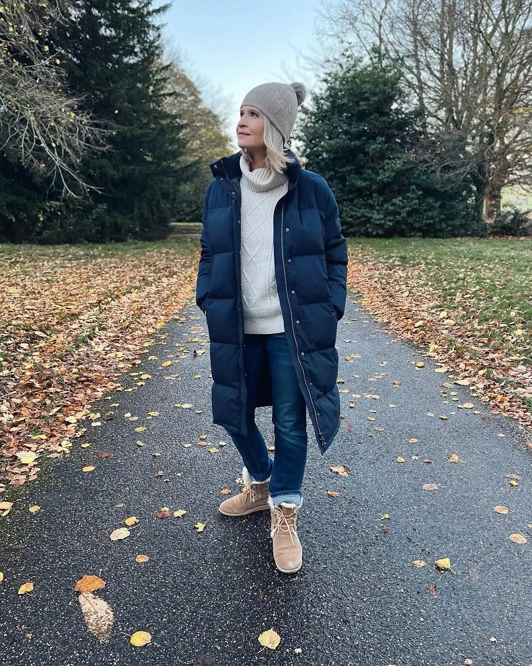 Navy long puffer with cream sweater and tan boots