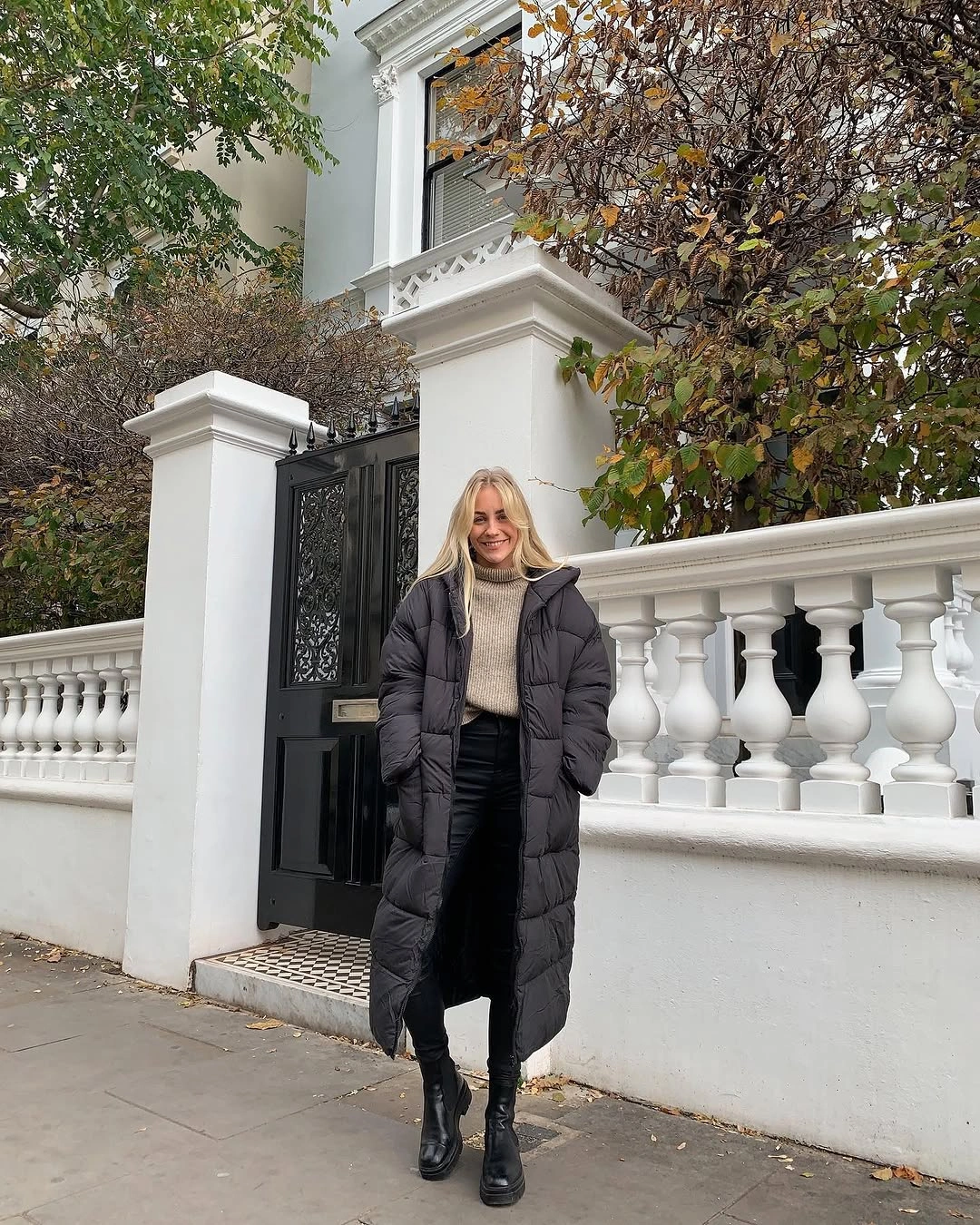 Black long puffer with pale sweater and black boots