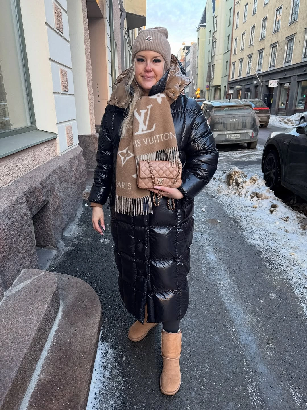 Shiny black long puffer with lettered scarf and beige boots