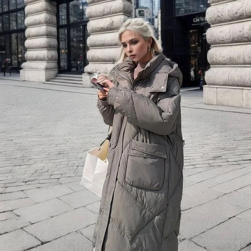 Long gray quilted coat with large pockets and white bag