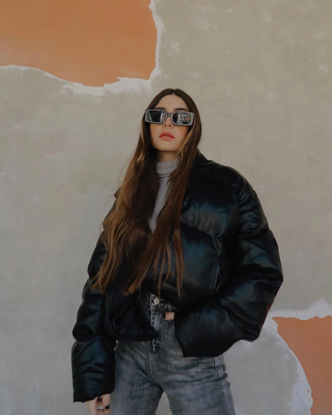 Glossy black short puffer with sunglasses and gray jeans