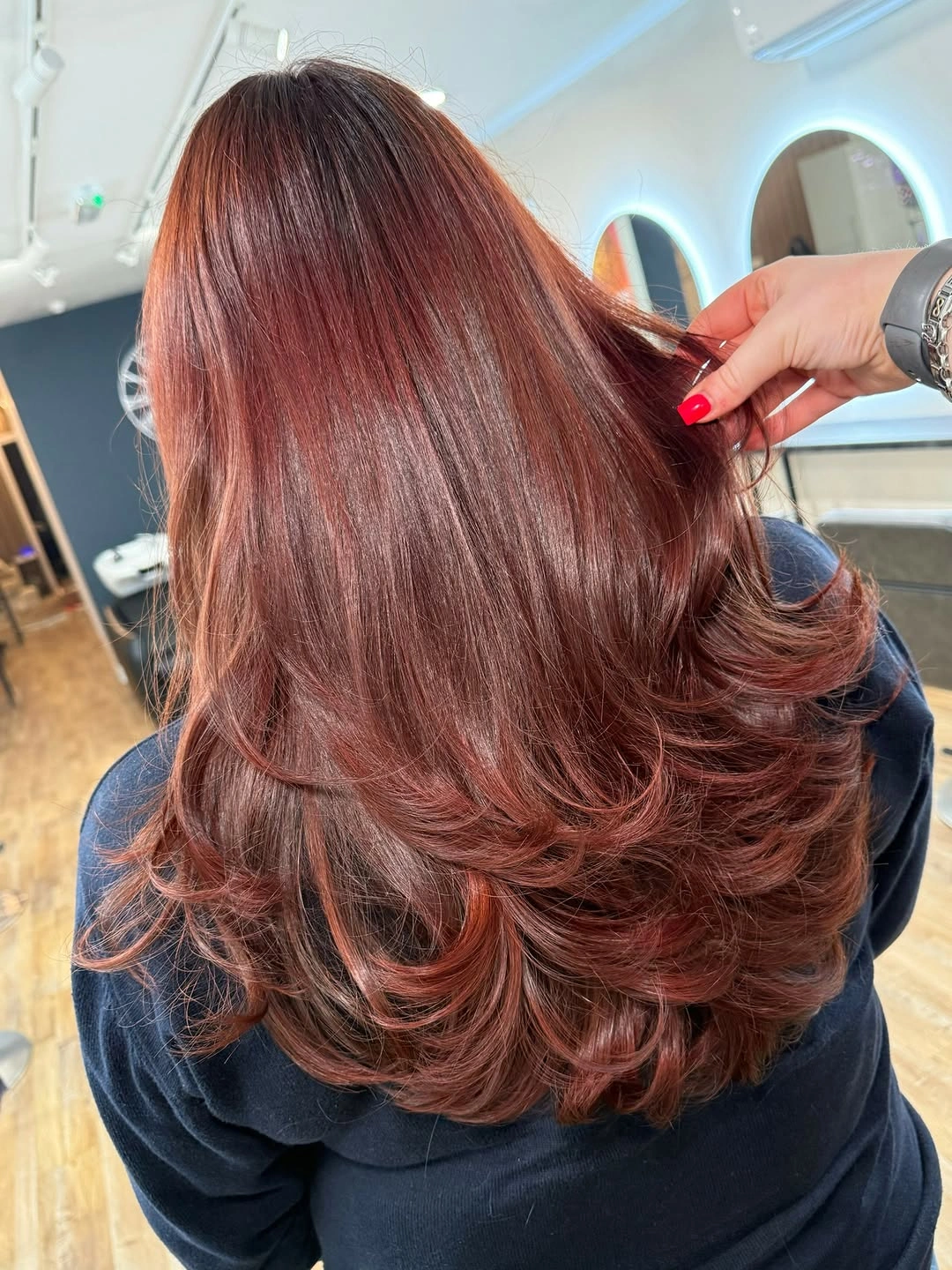 Rear view of long auburn layered hair with curled lower ends